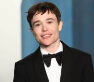 Elliot Page smile at the camera while wearing a white button up shirt, a black bow tie and black suit jacket