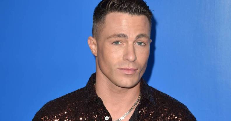 Colton Haynes wears a brown sequinned shirt as he stands in front of a blue background