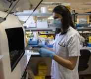 A medical laboratory technician places closes an automated nucleic acid extractor with suspected monkeypox samples inside