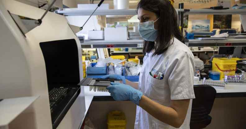 A medical laboratory technician places closes an automated nucleic acid extractor with suspected monkeypox samples inside