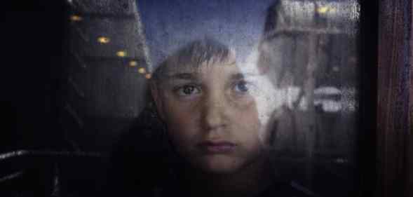 A young boy looks out through a window