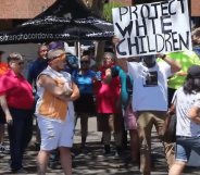 Anti-LGBTQ+ protestors holding a sign that reads 'protect white children'