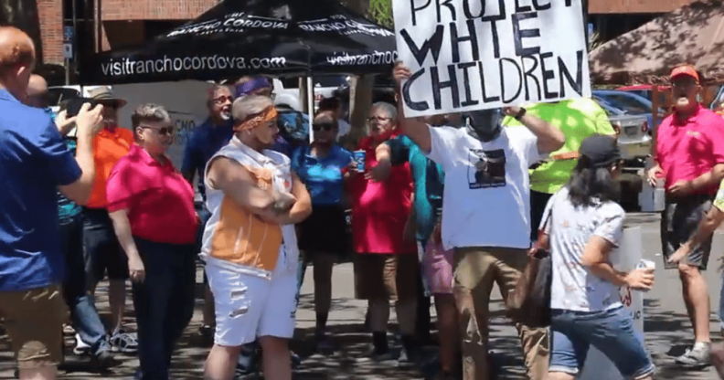 Anti-LGBTQ+ protestors holding a sign that reads 'protect white children'