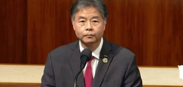 Ted Lieu, a Democrat lawmaker from California, stands at a podium before the state's House while wearing a white button up shirt, red tie and grey suit jacket