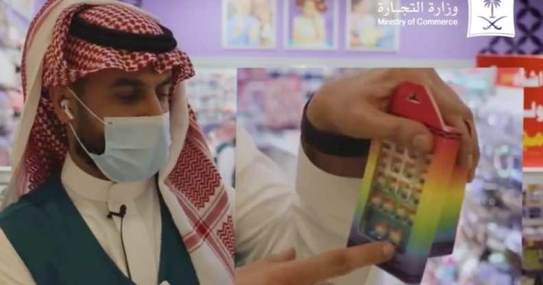 A Saudi Arabian official gestures towards a rainbow toy