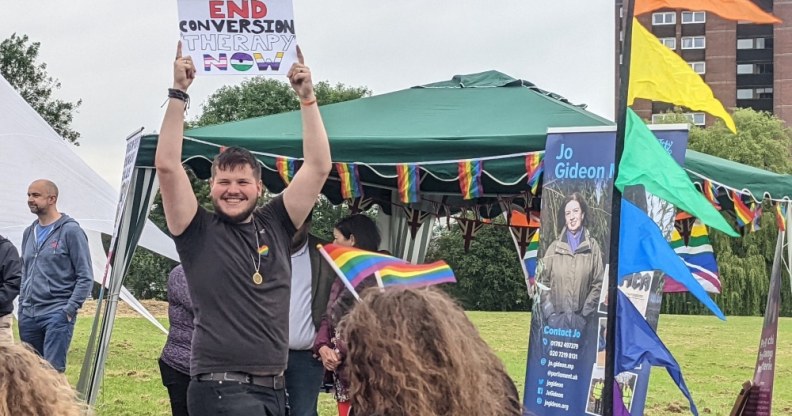 A student holding up a sign reading: 'End conversion therapy now'