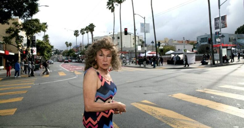 Donna in a multicoloured dress standing on a road