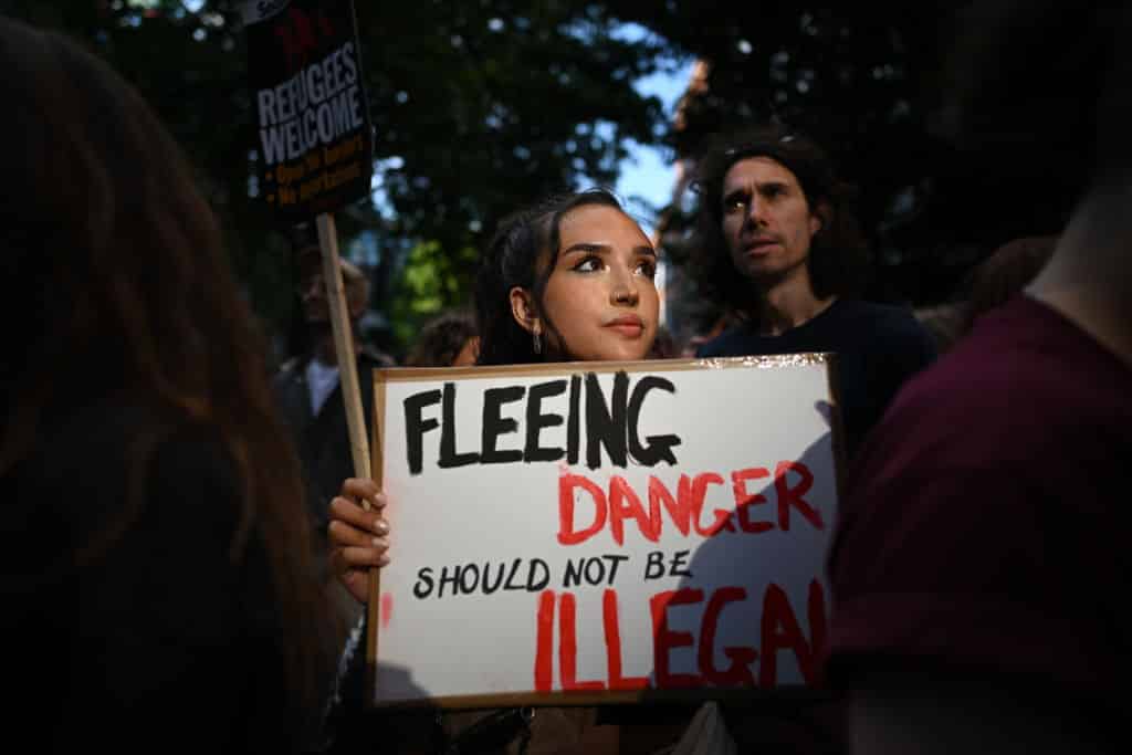 A woman holds a placard saying 'Fleeing danger should not be illegal' as people protest against the UK deportation flights to Rwanda outside the Home Office on June 13, 2022.