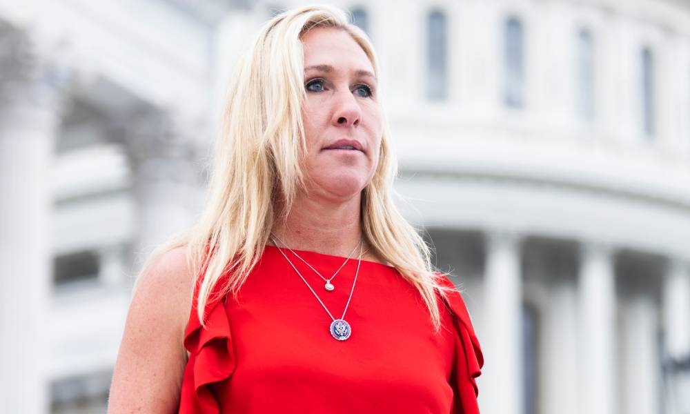 Marjorie Taylor Greene wears a red sleeveless top with little ruffles and two silver necklaces as she stands House steps of the US Capitol 