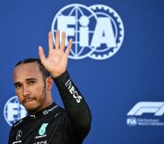 Lewis Hamilton waves as he walks back to the pits