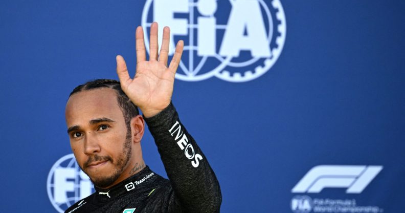 Lewis Hamilton waves as he walks back to the pits