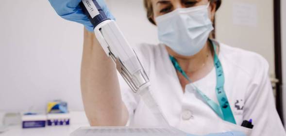 A nurse wearing a white outfit and facemask prepares a PCR for monkeypox testing