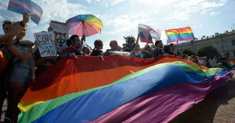 Activists wave rainbow flags during the gay pride rally in Saint Petersburg, Russia. The poeple hold up signs protesting against 'gay propaganda' laws and demanding change for the LGBTQ+ community