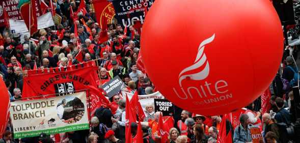 Protesters march with placards and trades union banners as part of a Trade Union Congress (TUC) demo