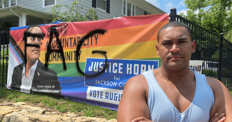 Justice Horn stands in front of his defaced banner