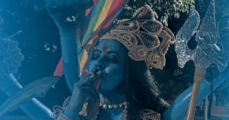 The poster for the upcoming documentary film Kaali, depicting a woman dressed as the goddess smoking a cigarette and holding a Pride flag