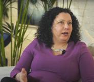 Maya Forstater wears a purple long sleeves top as she sits on a white couch during an interview