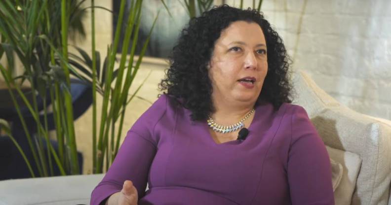 Maya Forstater wears a purple long sleeves top as she sits on a white couch during an interview