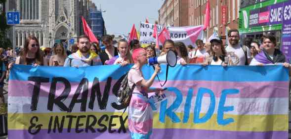 Crowds of at least a hundred (more not pictured), holding a banner that says Trans and Intersex Pride