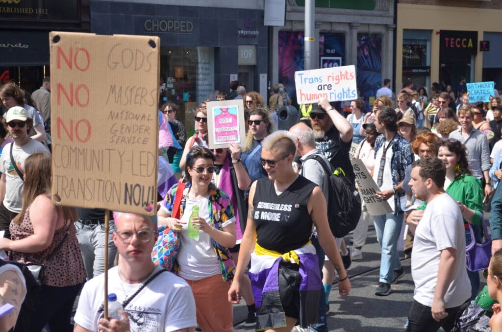 Crowds holding placards calling for 'community led transition' and saying 'trans rights are human rights'