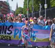 Trans and Intersex Pride co-founder Ollie Bell holds a megaphone in front of a banner during a Dublin Pride event