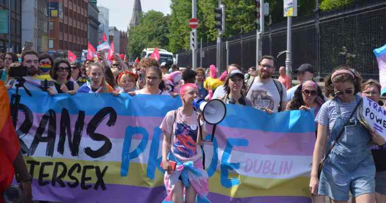 Trans and Intersex Pride co-founder Ollie Bell holds a megaphone in front of a banner during a Dublin Pride event