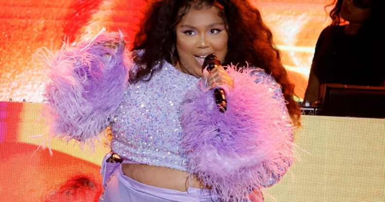 Lizzo in a purple two piece with furry sleeves, singing