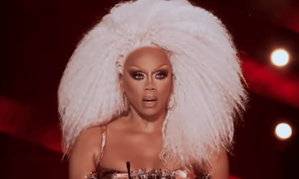 RuPaul with big blonde hair, looking shocked