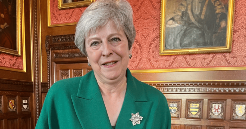 Theresa May in a House of Commons room lined with portraits