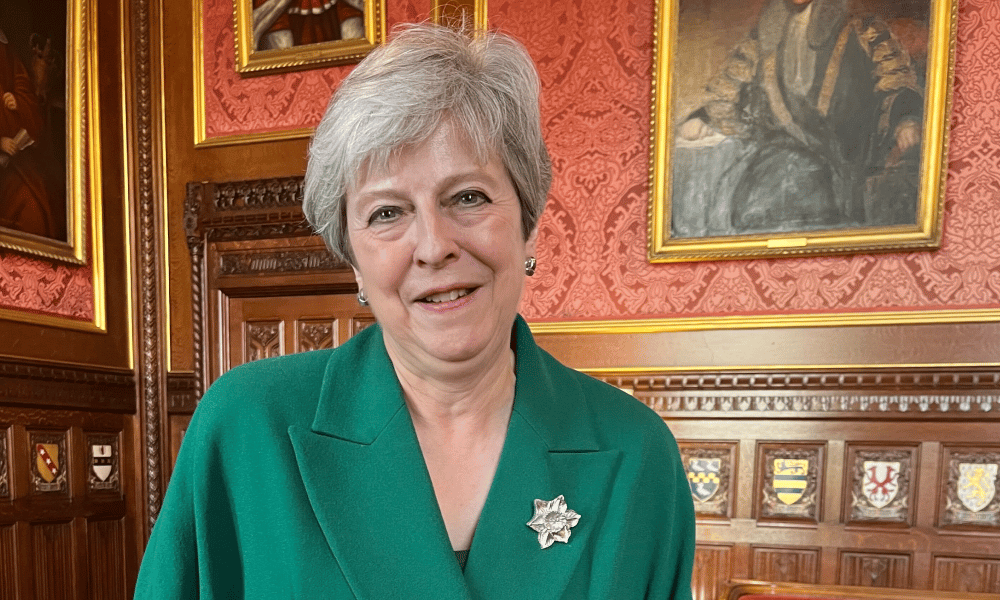 Theresa May in a House of Commons room lined with portraits