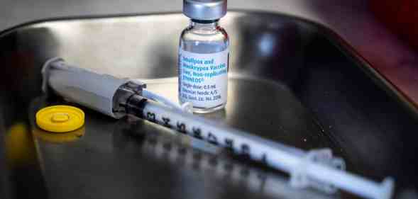 A bottle of monkeypox vaccine sits next to a needle on a tray