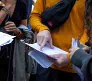 Several pupils gather together to read their A-level exam results in the UK. The JCQ is considering breaking down such data to be inclusive of non-binary pupils in the future