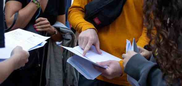 Several pupils gather together to read their A-level exam results in the UK. The JCQ is considering breaking down such data to be inclusive of non-binary pupils in the future