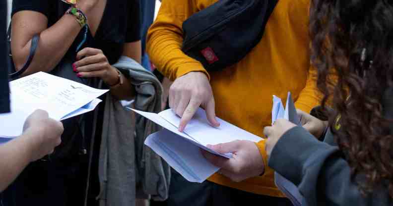 Several pupils gather together to read their A-level exam results in the UK. The JCQ is considering breaking down such data to be inclusive of non-binary pupils in the future