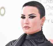 Demi Lovato wears dark clothing and matching dark eye makeup as they pose for the camera