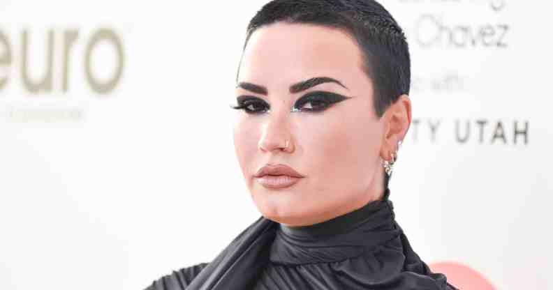 Demi Lovato wears dark clothing and matching dark eye makeup as they pose for the camera