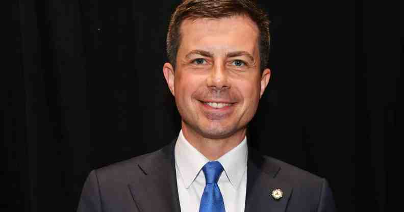 Pete Buttigieg smiles at the camera while wearing a suit and tie