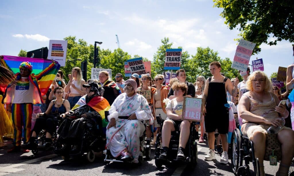 Several people gather for London Trans+ Pride holding up signs in support of the trans community