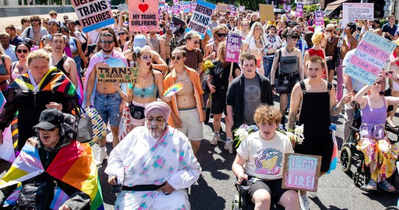 Several people gather for London Trans+ Pride holding up signs in support of the trans community