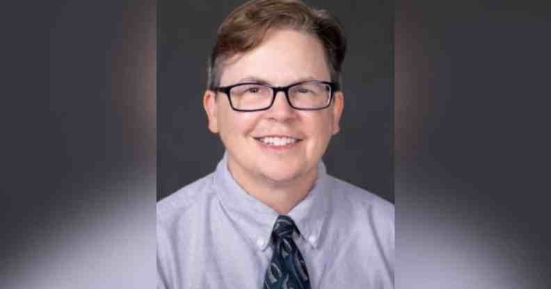 ESPN reporter MA Voepel wears a blue button up shirt with a dark tie as he stares at the camera