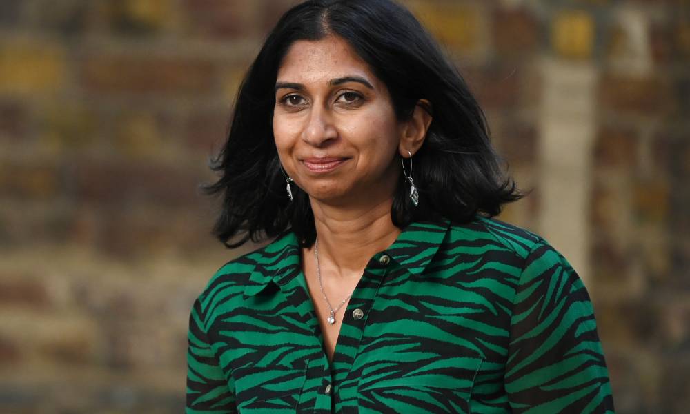 Suella Braverman wears a green and black animal patterned top as she walks outside