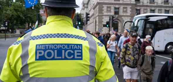 A Met Police officer looks towards people crossing the road