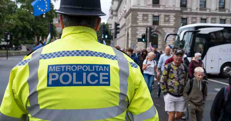 A Met Police officer looks towards people crossing the road