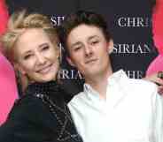 Anne Heche smiles while wearing a dark outfit as she stands next to her son Homer Laffoon who is wearing a white top