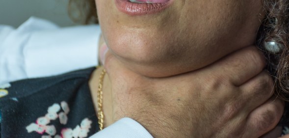 A stock photo of a woman with hands around her throat