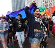 Participants, gathered in a crowd, hold up a rainbow LGBTQ+ flag during the Motor City Pride Parade at Detroit, Michigan