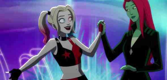 A still taken from the Harley Quinn animated series on HBO Max. In this image, Harley Quinn wears a black and red patterned outfit as she holds the hand of Poison Ivy, who is wearing dark clothing and staring at Harley