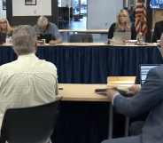 A row of board members sit to discuss the board agenda.