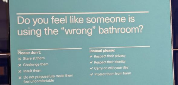 In this photograph, a sign says what to do if someone feels like there's a person in the 'wrong' bathroom