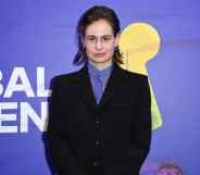 Photo of Redcar in a black suit with sheer purple shirt, against a purple backdrop